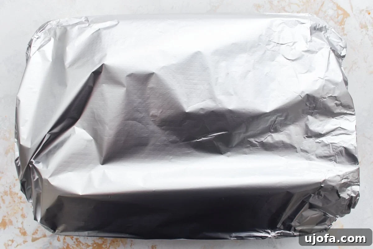 Irresistible Gluten-Free Lasagna 12 A baking dish containing the assembled gluten-free lasagna, covered tightly with aluminum foil, resting on a light countertop, ready to be baked.