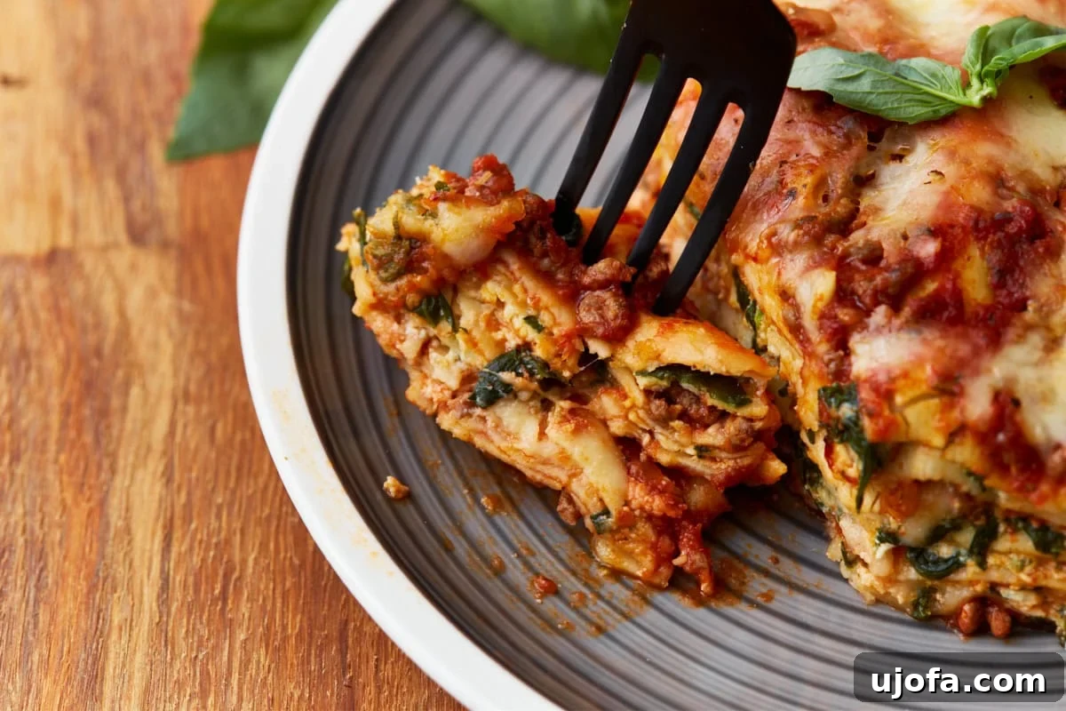 Irresistible Gluten-Free Lasagna 15 A black fork lifting a perfect, layered piece of gluten-free lasagna from the baking dish, highlighting its distinct layers and appealing texture.