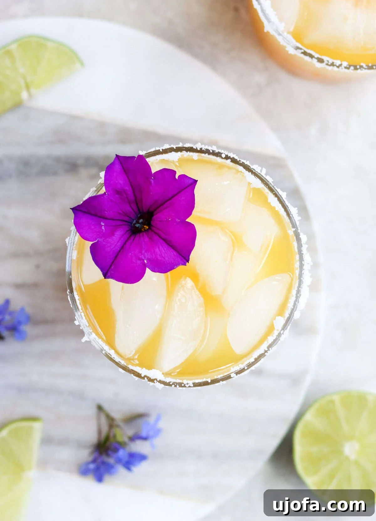 Exotic Passion Fruit Margarita Bliss 6 An overhead view of a vibrant passion fruit margarita, expertly garnished with a purple tropical flower and a lime wedge on a salted rim.