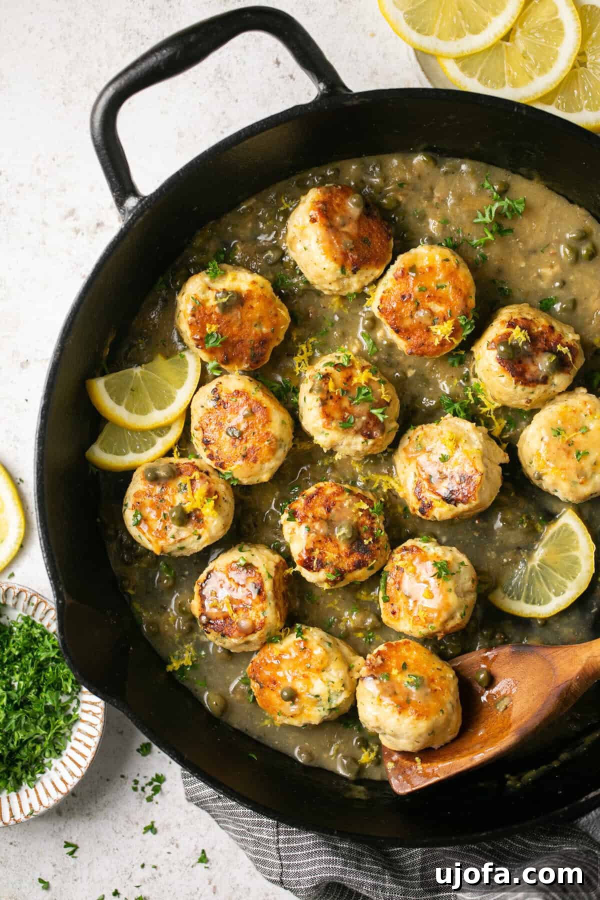 Zesty Gluten-Free Chicken Piccata Meatballs 5 a skillet with chicken piccata meatballs with lemon as garnish