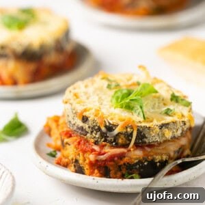 3 servings of baked eggplant parmesan on white plates with a silver fork