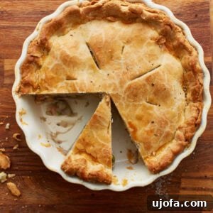 The Ultimate Gluten-Free Chicken Pot Pie 6 overhead view of a gluten-free chicken pot pie in a white pie pan on a wooden countertop with 2 slices gone and another slice cut