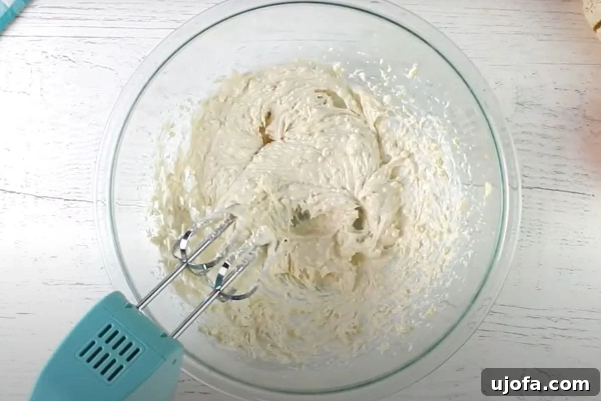 Decadent Gluten-Free Pumpkin Spice Squares 12 Softened cream cheese and butter are being vigorously beaten together with an electric hand mixer in a clear glass bowl, transforming into a creamy, pale mixture that will form the base of the delicious frosting.