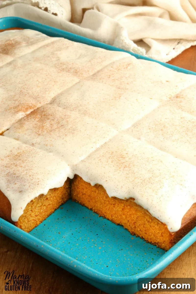 Decadent Gluten-Free Pumpkin Spice Squares 4 Several gluten-free pumpkin bars, generously topped with swirling cream cheese frosting, are arranged on a rustic white serving tray, ready to be enjoyed.