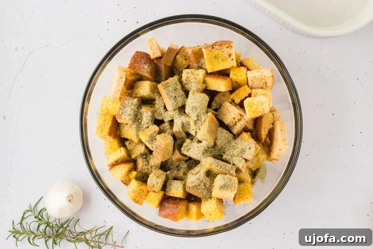 Savory Gluten-Free Cornbread Dressing 15 A glass bowl filled with cubed gluten-free cornbread and gluten-free bread, evenly sprinkled with the aromatic herb and spice mix.