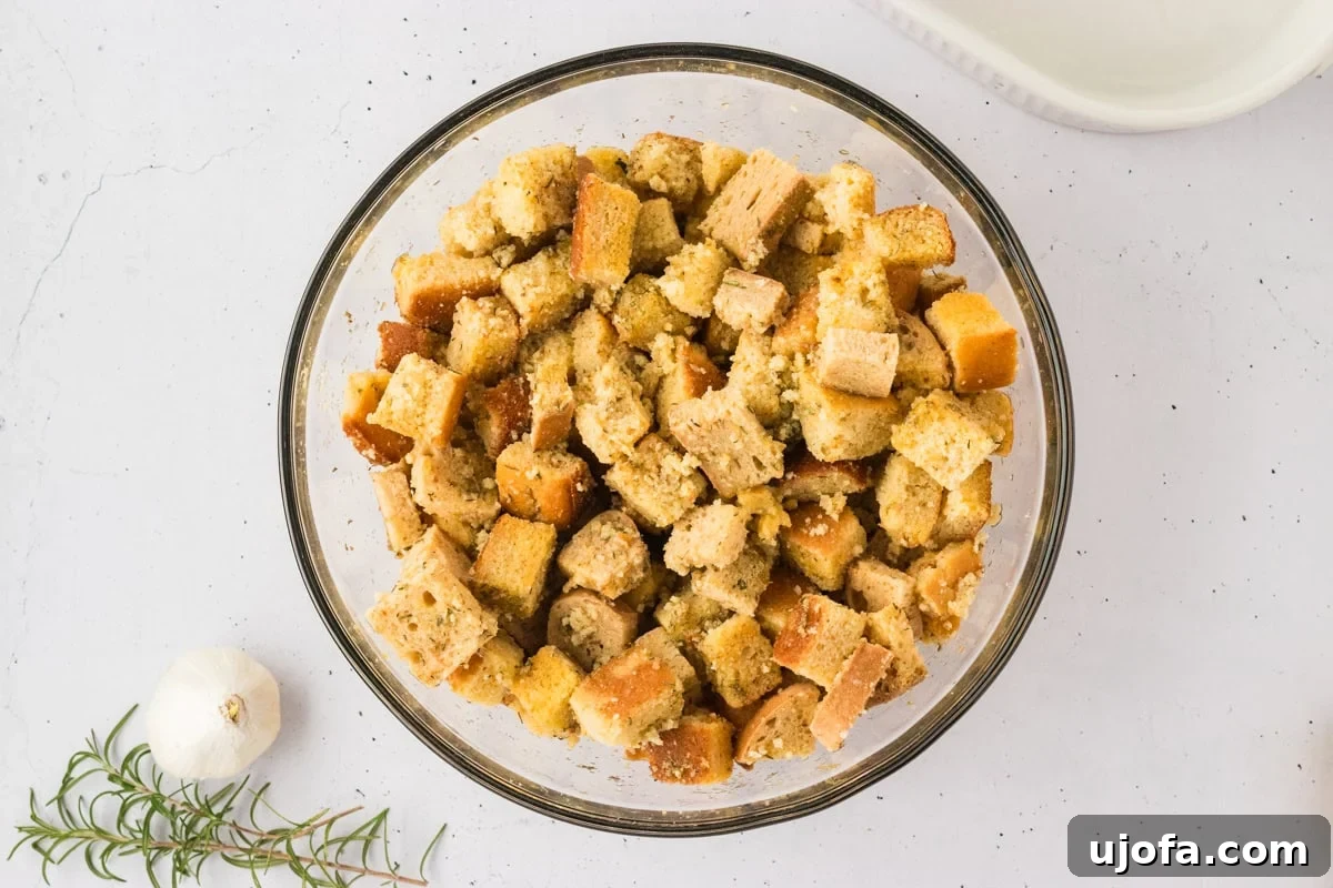 Savory Gluten-Free Cornbread Dressing 16 The cubed gluten-free cornbread and bread fully mixed with herbs, seasonings, and chicken broth in a glass bowl, moistened and ready for the next step.