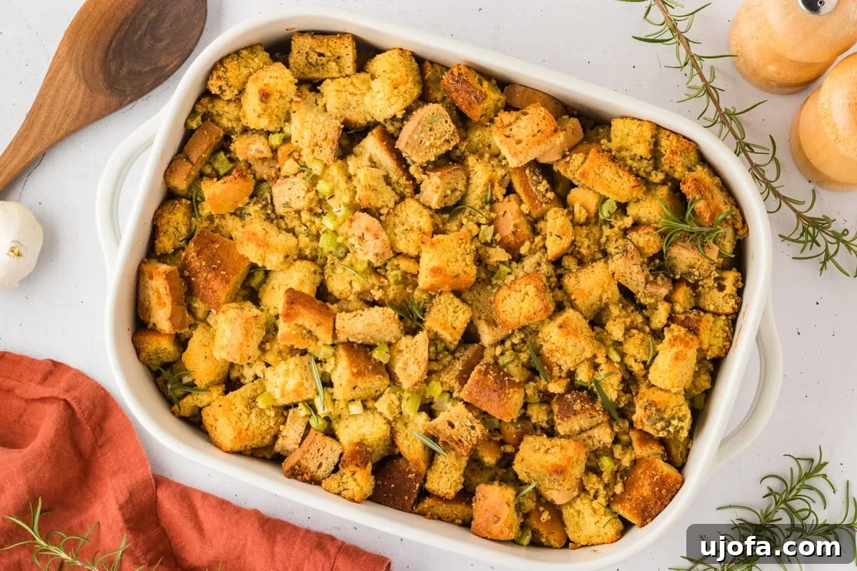 Savory Gluten-Free Cornbread Dressing 18 A golden-brown, crispy-topped gluten-free cornbread stuffing in a white casserole dish, garnished with fresh rosemary, ready to serve.