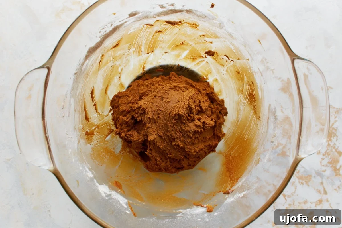 Guilt-Free Gingerbread Bliss 10 The combined wet and dry ingredients forming a thick, golden-brown gluten-free gingerbread dough in a glass mixing bowl, after being fully mixed.
