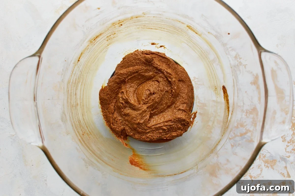 Guilt-Free Gingerbread Bliss 8 A cracked large egg, dark molasses, and pure vanilla extract have been added to the creamed butter and sugar mixture in a glass bowl, ready to be blended for the gluten-free gingerbread dough.
