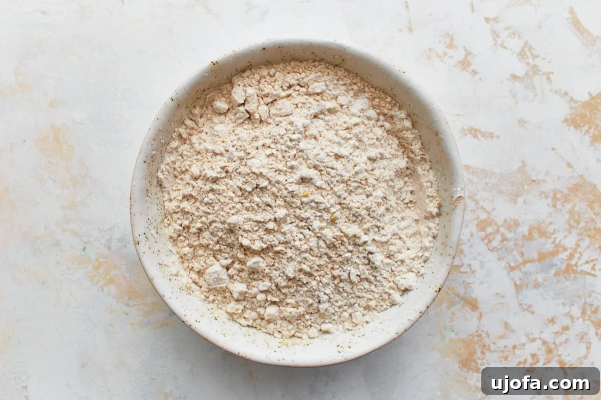 Guilt-Free Gingerbread Bliss 9 A medium-sized mixing bowl containing a dry ingredient blend of gluten-free all-purpose flour, baking soda, salt, ground ginger, cinnamon, nutmeg, and allspice, ready for whisking.
