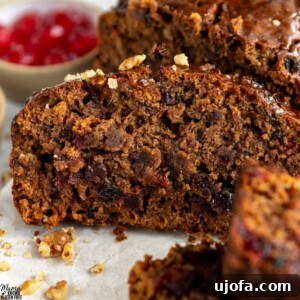A festive gluten-free fruit cake, richly studded with candied fruit and nuts, ready to be sliced and served for holiday celebrations.