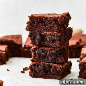 A delectable stack of four rich gluten-free brownies, showcasing their fudgy texture and appealing dark chocolate color.