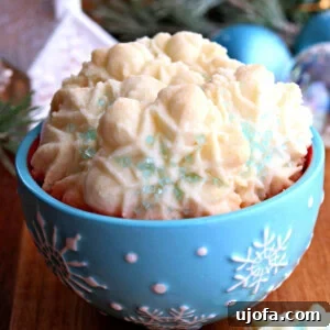 A festive blue snowflake bowl filled with delicate gluten-free almond spritz cookies, set against a backdrop of twinkling Christmas decorations.