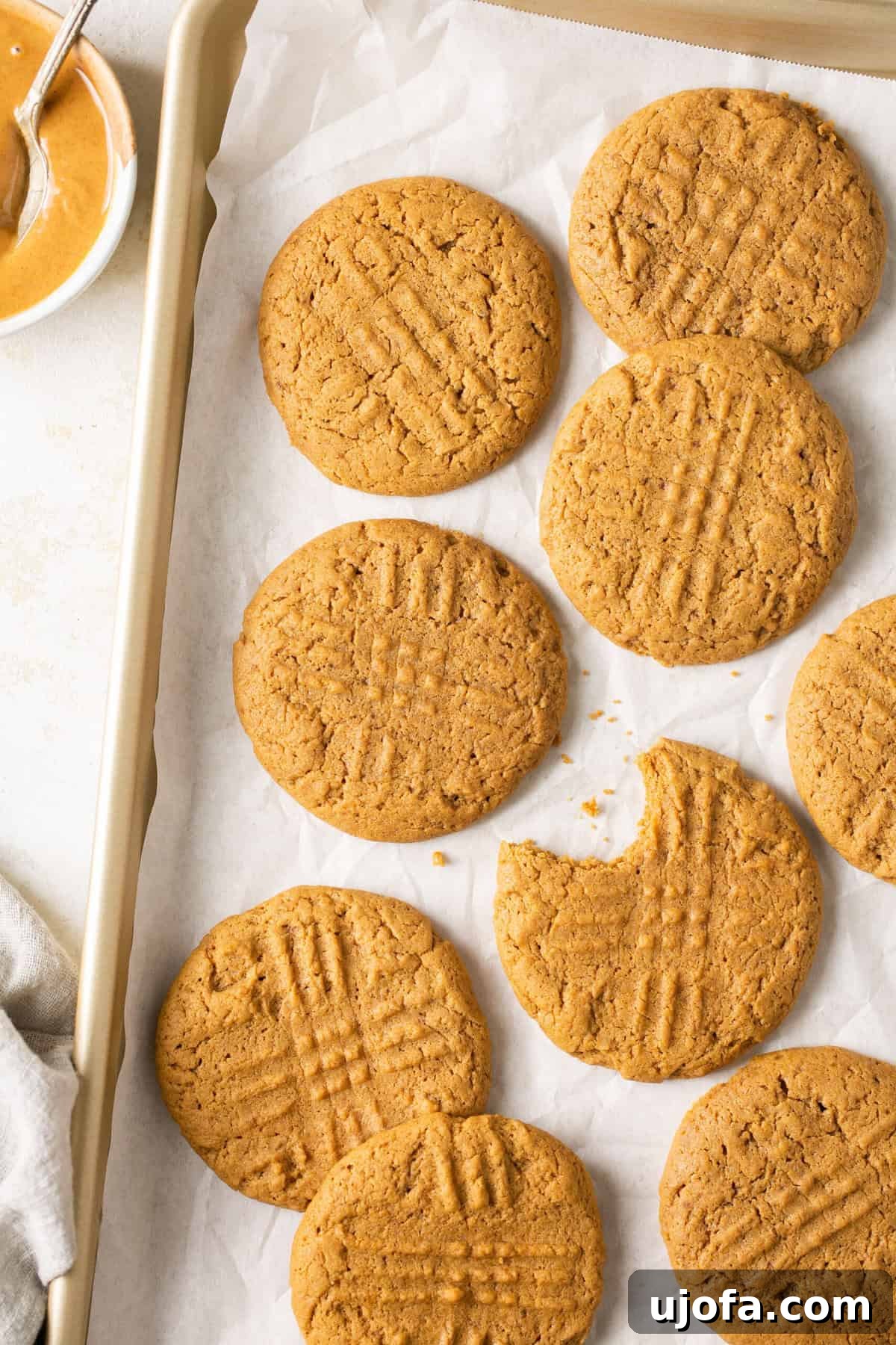 A baking sheet lined with parchment paper, showcasing a fresh batch of golden-brown gluten-free peanut butter cookies ready to be enjoyed.