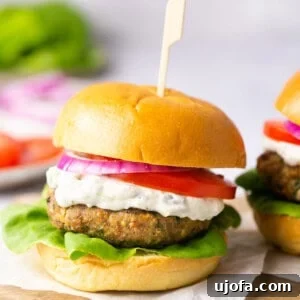 A turkey burger on a gluten free bun with tzatziki sauce, tomato, lettuce, and red onion