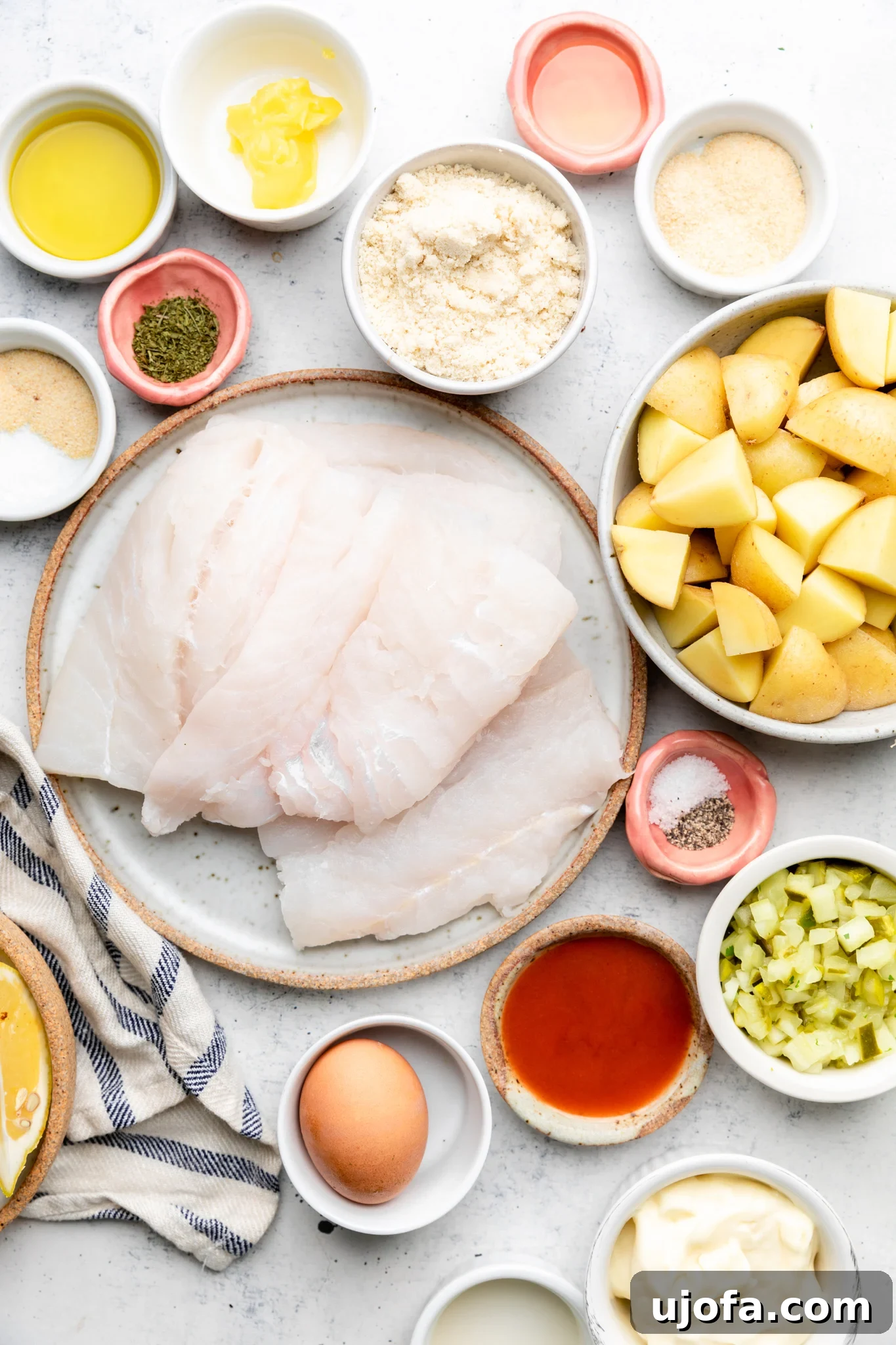 Ingredients laid out for preparing gluten-free fish and chips, including cod fillets, potatoes, eggs, almond flour, and spices.