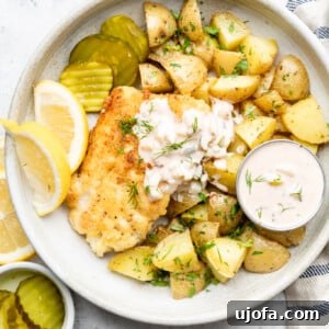 Gluten-free fish and chips served with fresh lemon, pickles, and a bowl of tartar sauce.