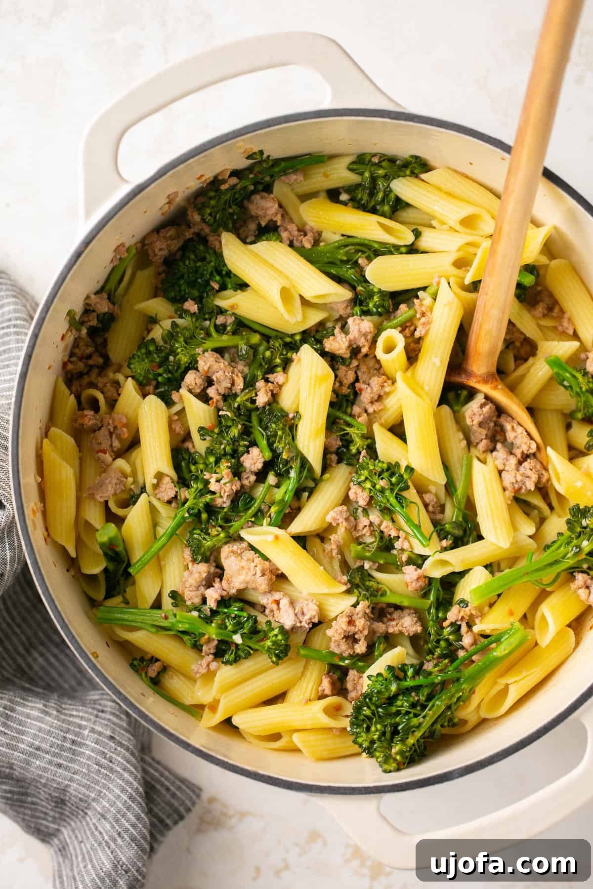 Hearty Sausage and Broccolini Pasta 5 A white Dutch oven filled with a generous portion of sausage broccolini pasta, ready to be served.