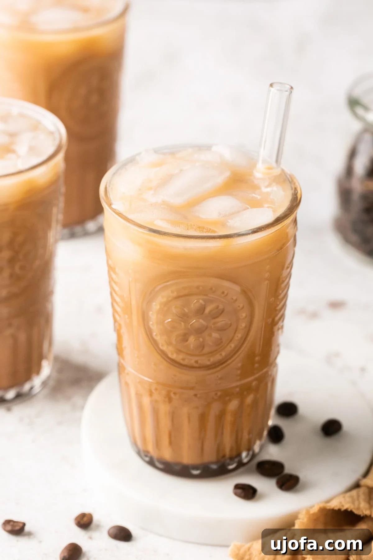 Close-up of a beautifully crafted iced coffee in a glass, with ice and a straw, showcasing its refreshing appeal.