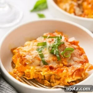 Instant Pot Lasagna in a white bowl topped with fresh basil, with a fork resting beside it, highlighting its deliciousness.