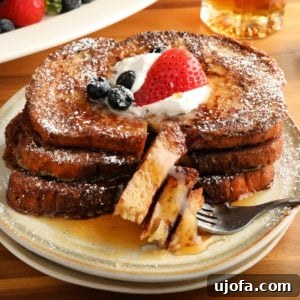 gluten-free French Toast topped with berries, whipped cream, and syrup on a white plate with a fork