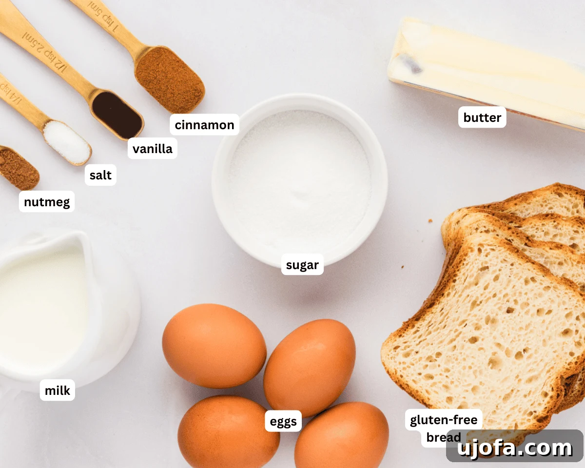 Gluten-free french toast ingredients laid out on a white surface, including eggs, milk, cinnamon, nutmeg, salt, vanilla, sugar, gluten-free bread, and butter.