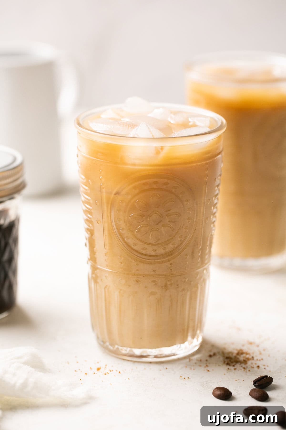 An up close shot of a tall glass filled with brown sugar shaken espresso and ice, with creamy oat milk poured on top, ready to be enjoyed.