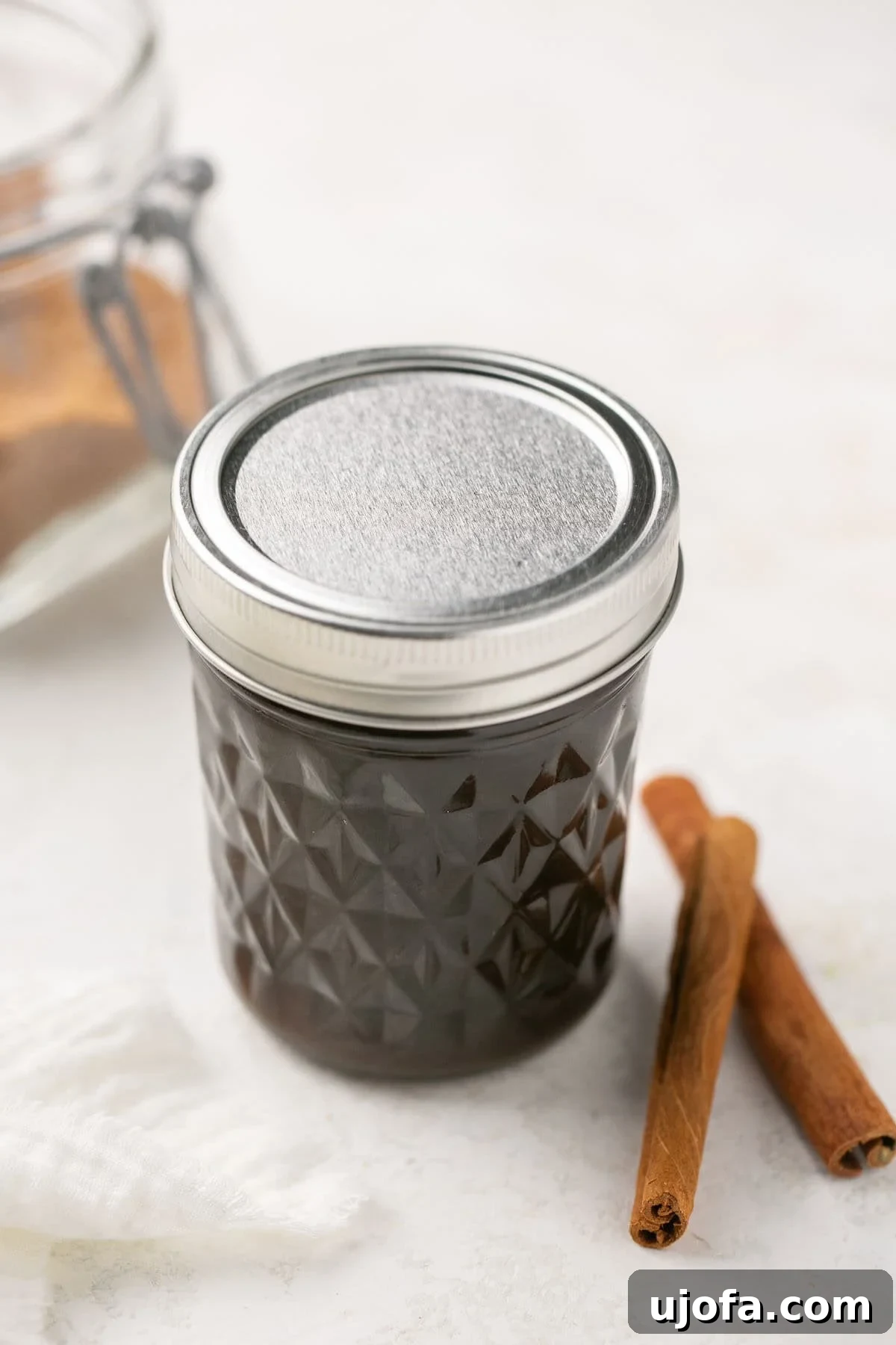 A closeup of rich brown sugar syrup in a mason jar with a silver lid, illustrating how to store homemade syrup for later use.