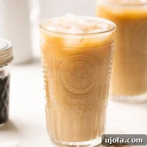 brown sugar shaken espresso in a glass with coffee beans and brown sugar syrup in the background