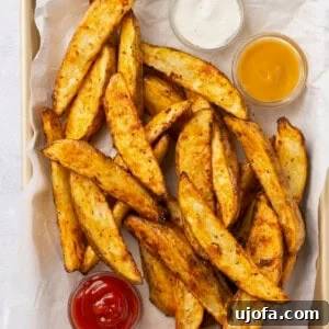 Golden Air-Fried Potato Wedges 7 air fryer potato wedges in a basket with 3 dipping sauces