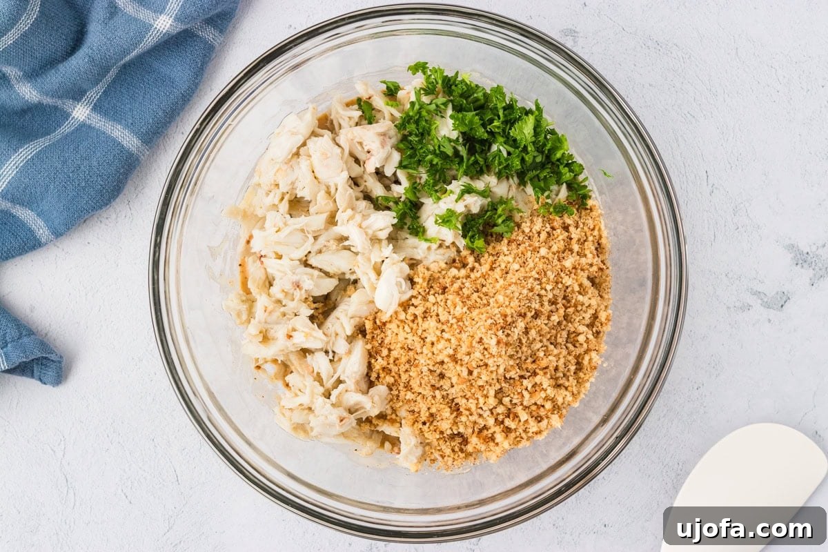 A bowl of lump crab meat, finely chopped parsley, and a mound of gluten-free breadcrumbs before being gently folded into the wet mixture.