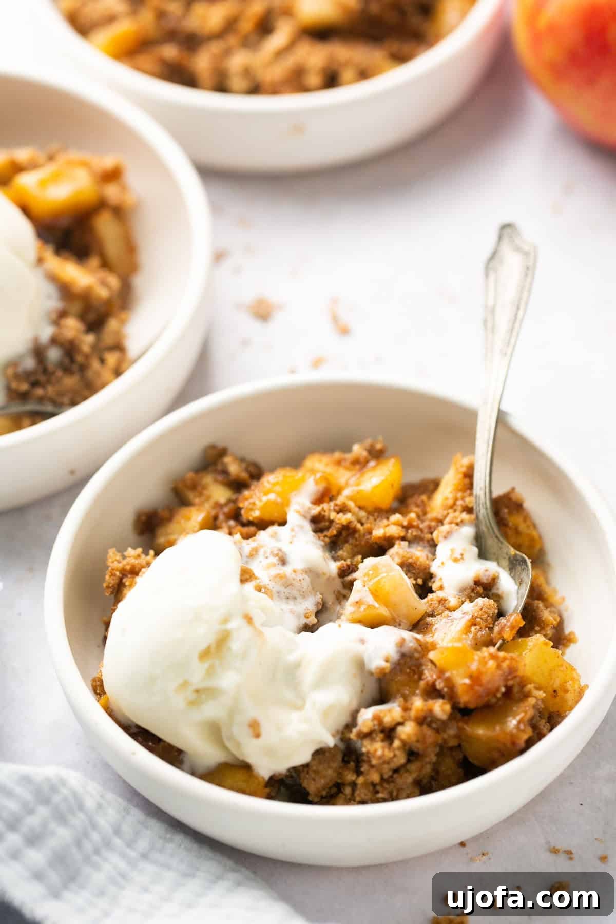 Guilt-Free Apple Crumble 6 a slice of apple crumble in a white bowl topped with ice cream and a silver spoon