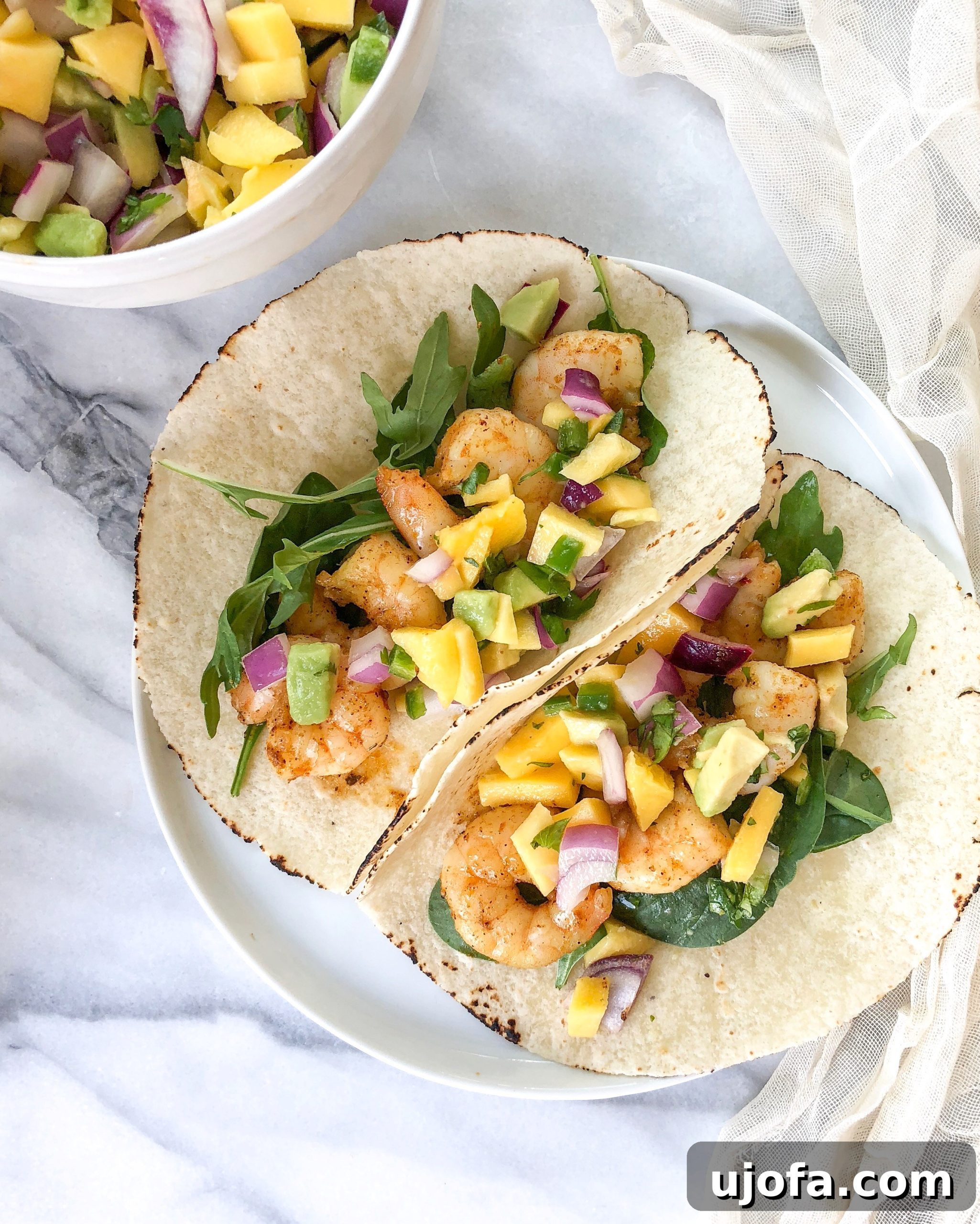 A bowl of fresh mango avocado salsa with colorful ingredients visible, served with tortilla chips.