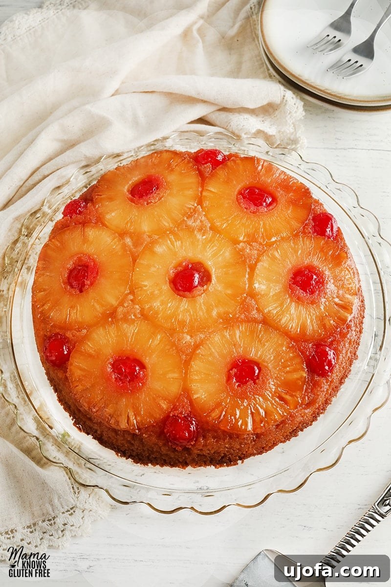 Delicious Gluten-Free Pineapple Upside Down Cake Dairy-Free Friendly 5 A beautifully presented gluten-free pineapple upside down cake on a decorative cake plate, surrounded by complementary plates and a cake cutter, hinting at a delightful dessert experience.