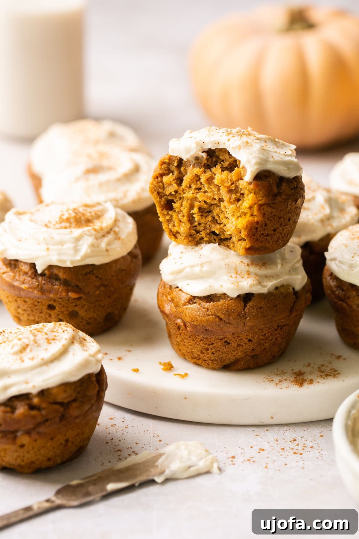 Moist Dairy-Free Pumpkin Muffins with Tangy Cream Cheese Frosting 2 A close-up photo of fluffy gluten-free pumpkin muffins generously topped with creamy dairy-free frosting, inviting a delightful autumn taste experience.