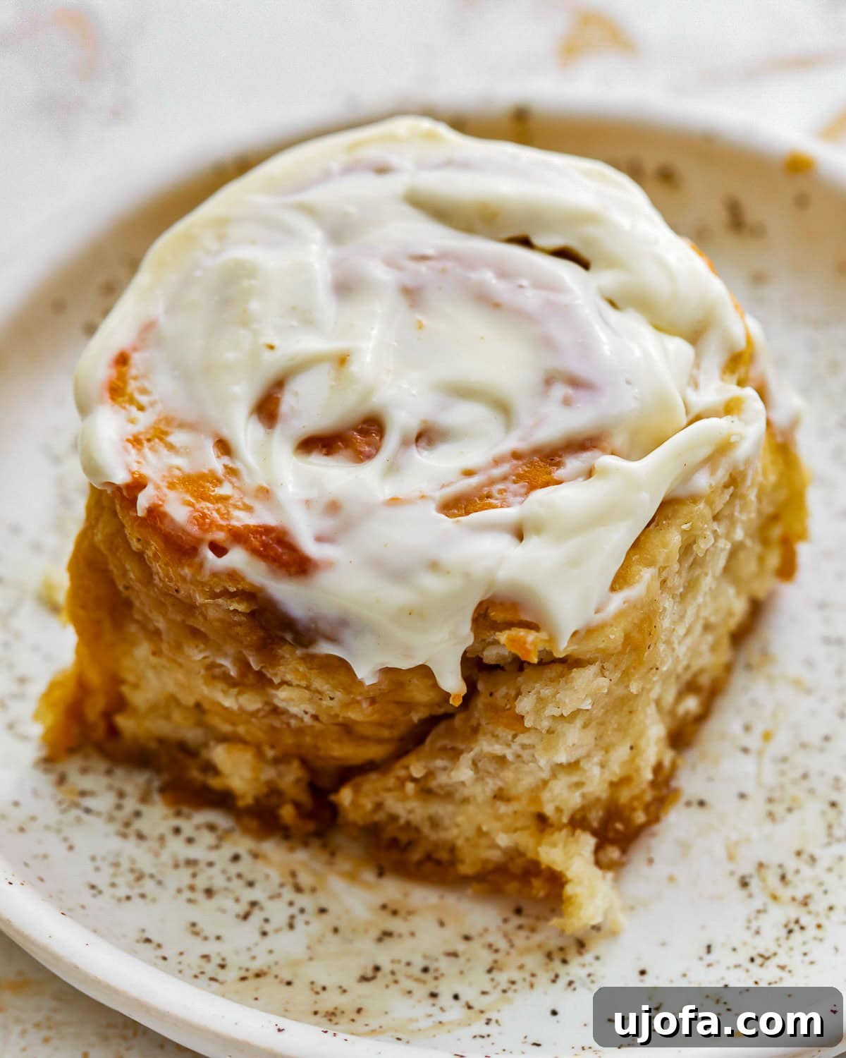 Irresistible Gluten-Free Cinnamon Buns 2 up close gluten free cinnamon roll, topped with a thick layer of white cream cheese frosting.