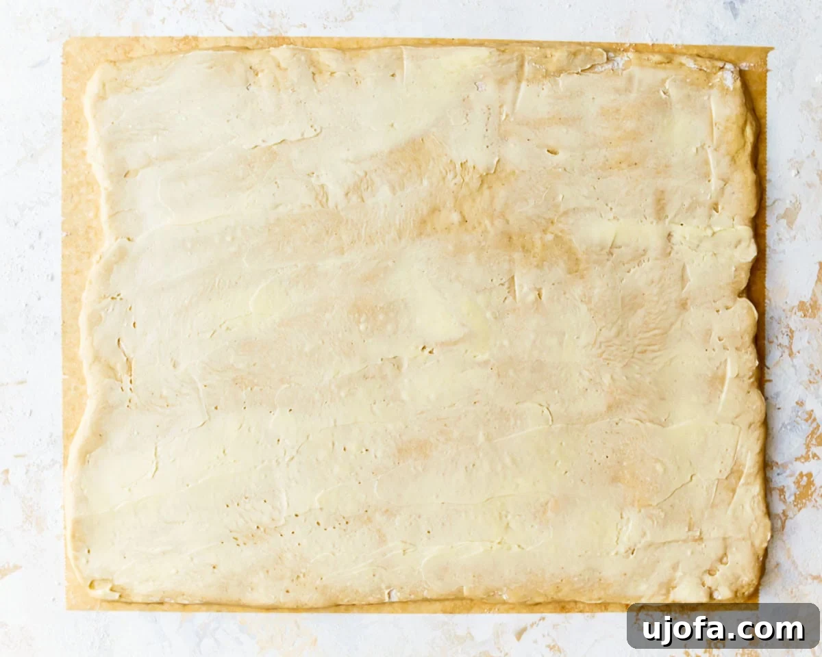 Irresistible Gluten-Free Cinnamon Buns 14 A rectangular sheet of gluten-free dough spread evenly with the softened butter and vanilla mixture.