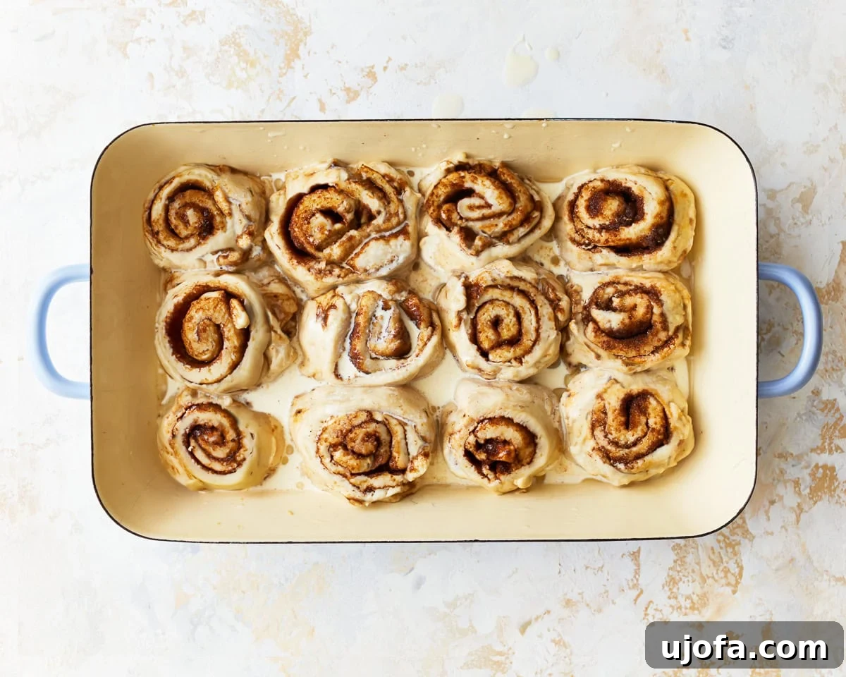 Irresistible Gluten-Free Cinnamon Buns 18 Unbaked gluten-free cinnamon rolls arranged in a greased 9x13-inch baking dish, ready for baking.