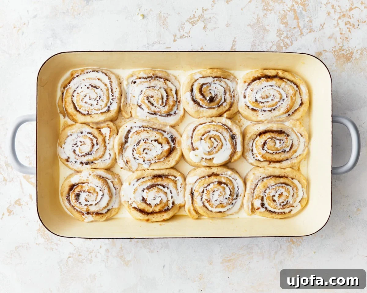 Irresistible Gluten-Free Cinnamon Buns 19 Warm heavy cream poured over unbaked gluten-free cinnamon rolls in a baking tray, ensuring moisture.