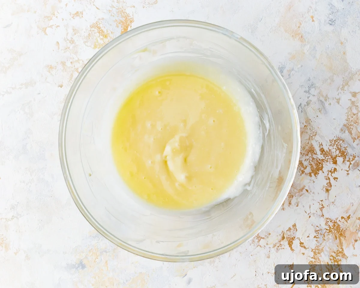 Irresistible Gluten-Free Cinnamon Buns 20 Wet ingredients for cream cheese frosting—cream cheese, butter, and vanilla extract—in a glass bowl, ready to be beaten.