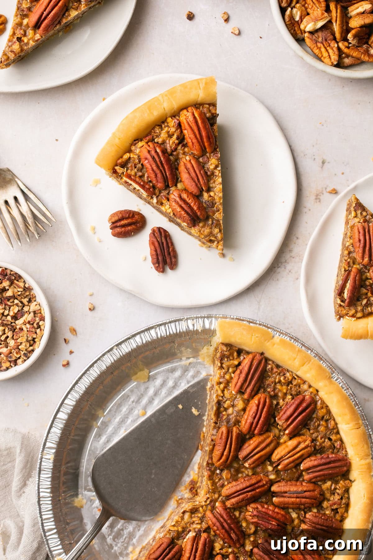 Pure Delight Gluten-Free Dairy-Free Pecan Pie No Corn Syrup 6 An inviting overhead shot of a slice of pecan pie, elegantly topped with pecan halves, resting next to a half-eaten pie in a foil plate.