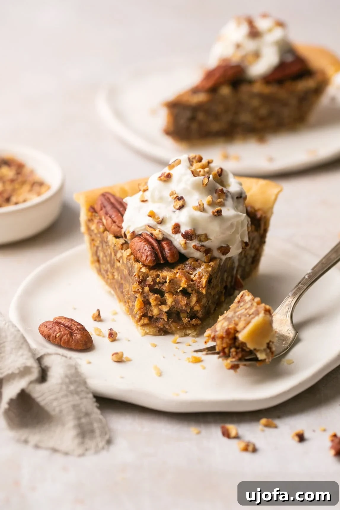 Pure Delight Gluten-Free Dairy-Free Pecan Pie No Corn Syrup 7 A detailed close-up photo of a slice of pie on a white plate, with a bite taken out, revealing its rich texture and satisfying filling.