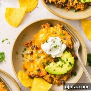 Loaded taco skillet in a bowl with sour cream, avocado, and chips