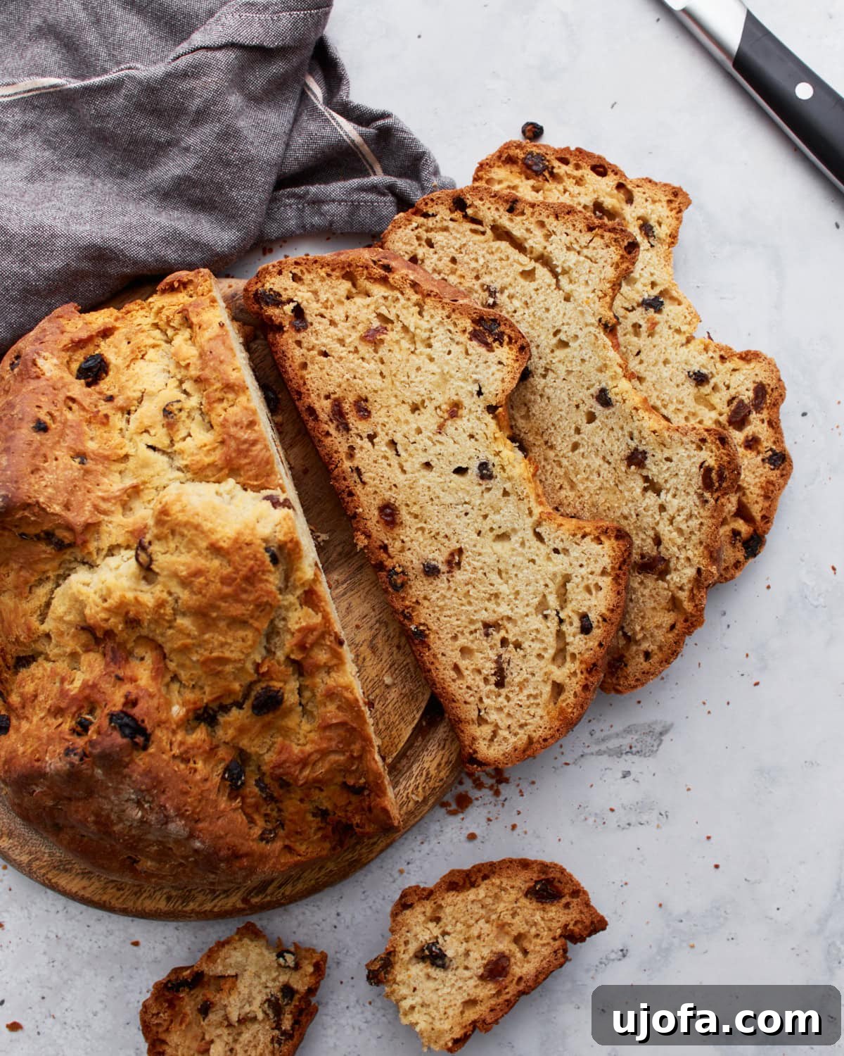 Deliciously Simple Gluten-Free Irish Soda Bread 2 A round loaf of golden-brown gluten-free Irish soda bread, sliced to reveal its soft interior dotted with raisins.