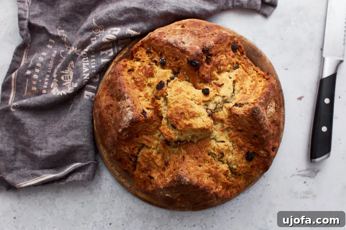 Deliciously Simple Gluten-Free Irish Soda Bread 18 A rustic loaf of gluten-free Irish soda bread on a wooden serving board, accompanied by a kitchen towel and a knife