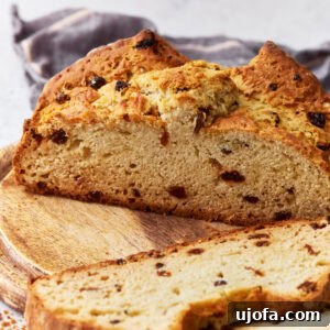 Sliced gluten-free Irish soda bread, highlighting its soft crumb and raisins throughout, placed on a wooden board