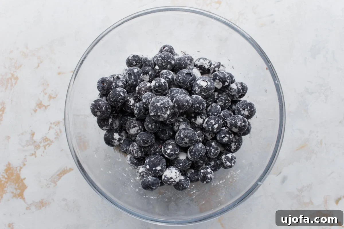 Deliciously Easy Gluten-Free Blueberry Muffins 10 Fresh blueberries coated in a light dusting of flour inside a clear glass bowl, ready to be incorporated into the muffin batter.