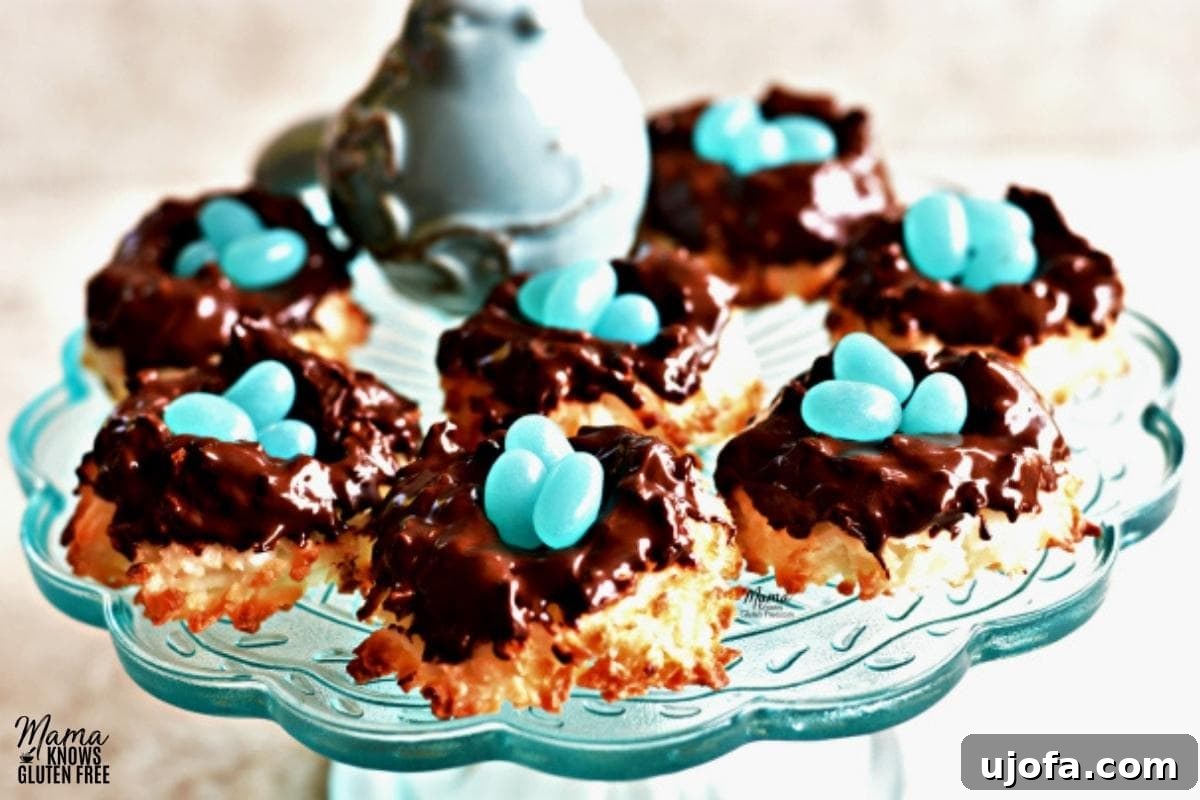 Sweet & Chewy Gluten-Free Coconut Macaroons 5 Gluten-free coconut macaroon nest cookies adorned with small blue bird figurines and jelly beans, arranged on a blue cake plate.