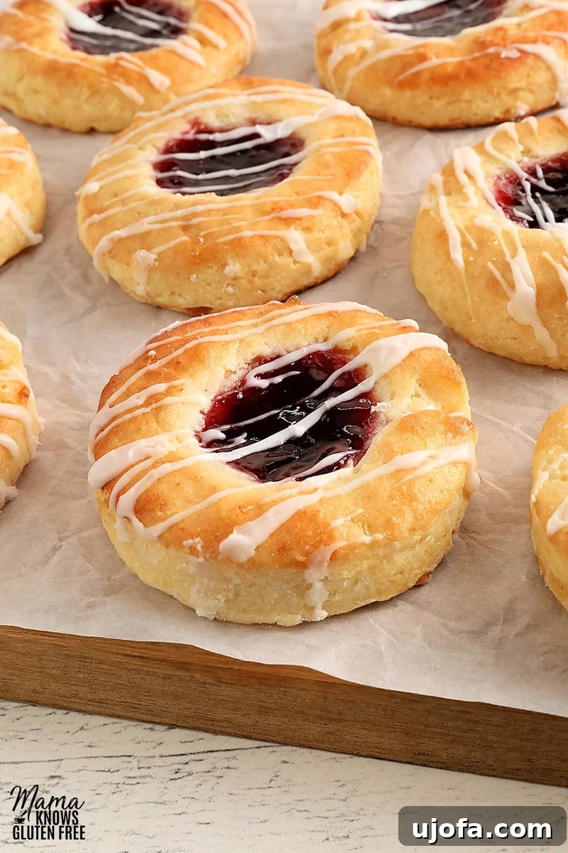 Gluten-free jam-filled Danish pastries on parchment paper, beautifully golden and glazed