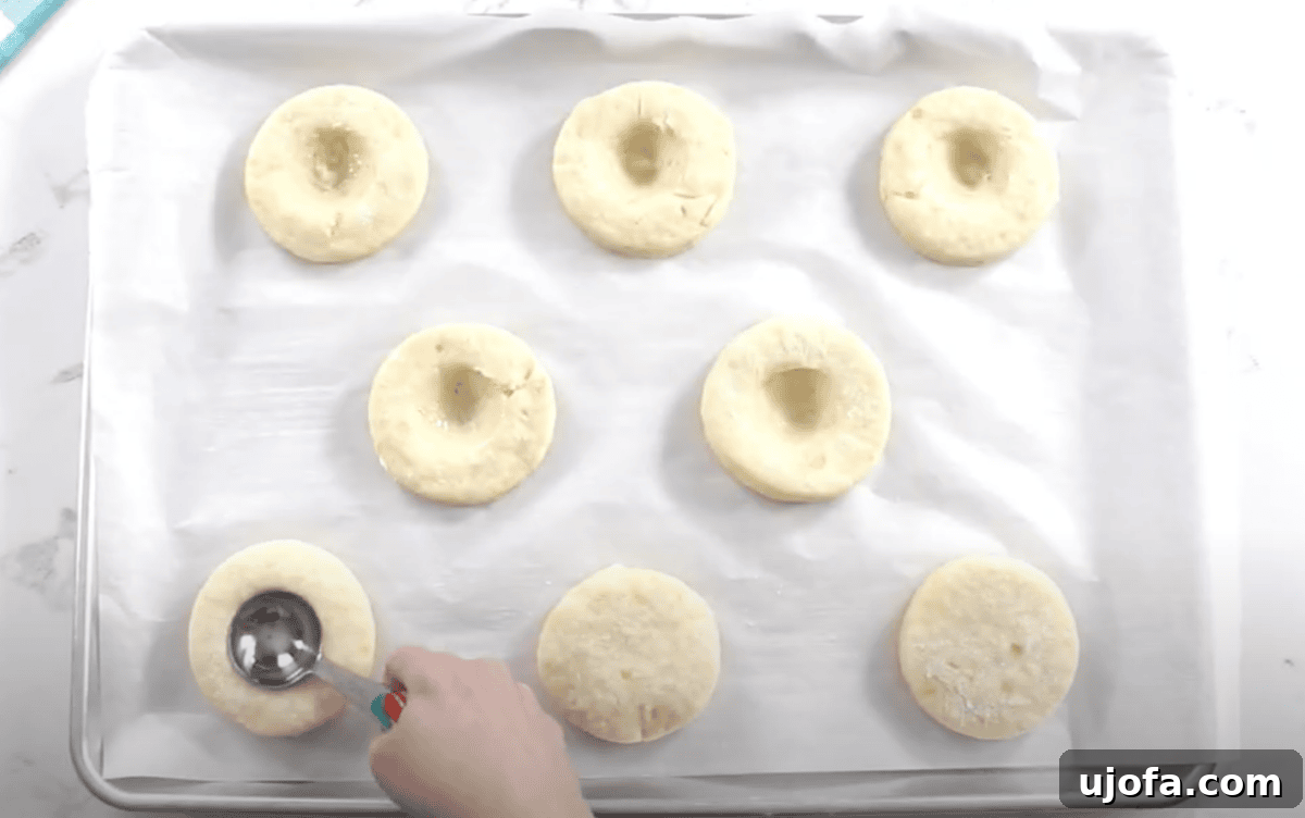 A spoon presses the center of each risen dough round to create a well for filling.